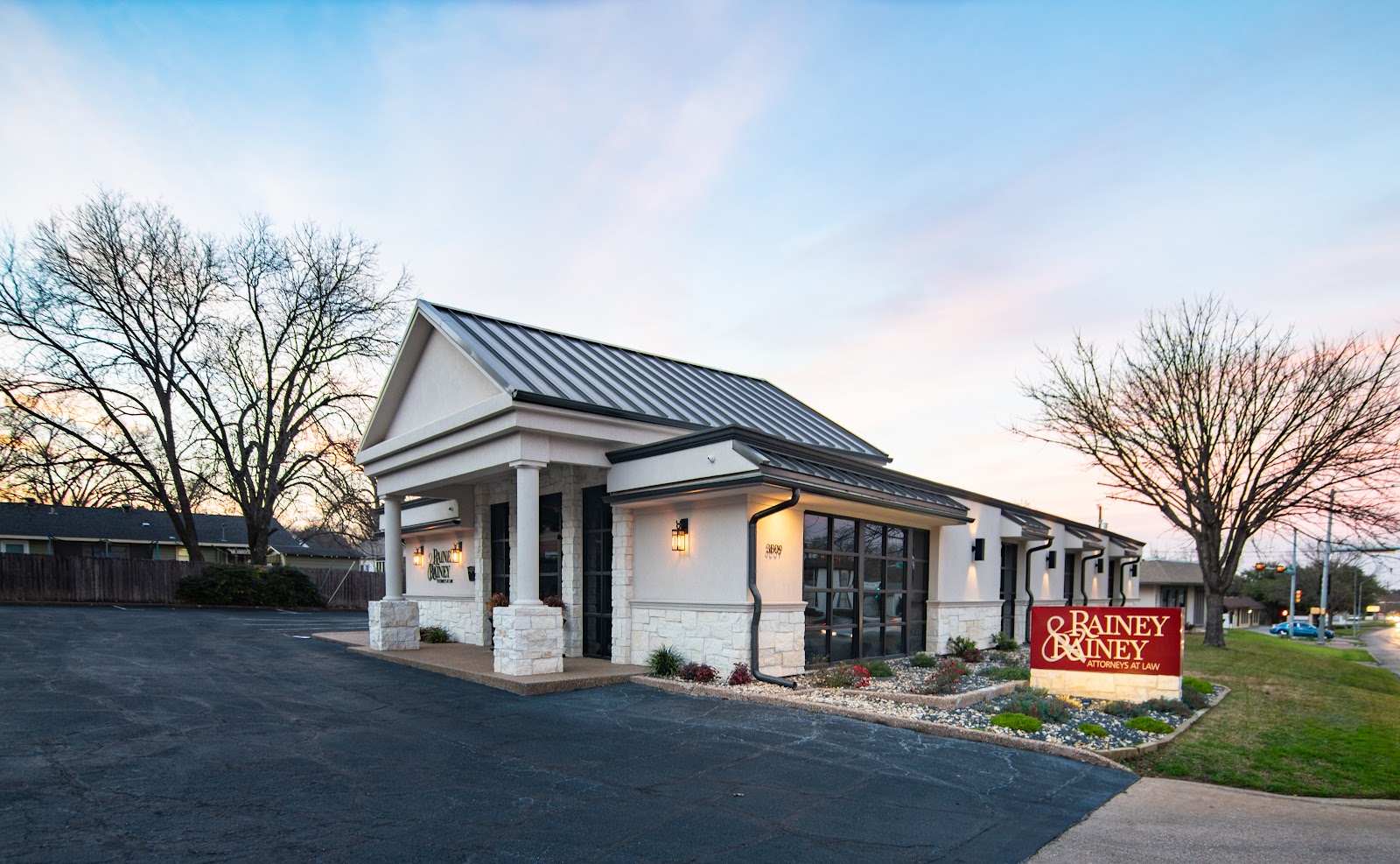 The Rainey & Rainey office building in Waco at dusk, with the firm's monument sign at the street