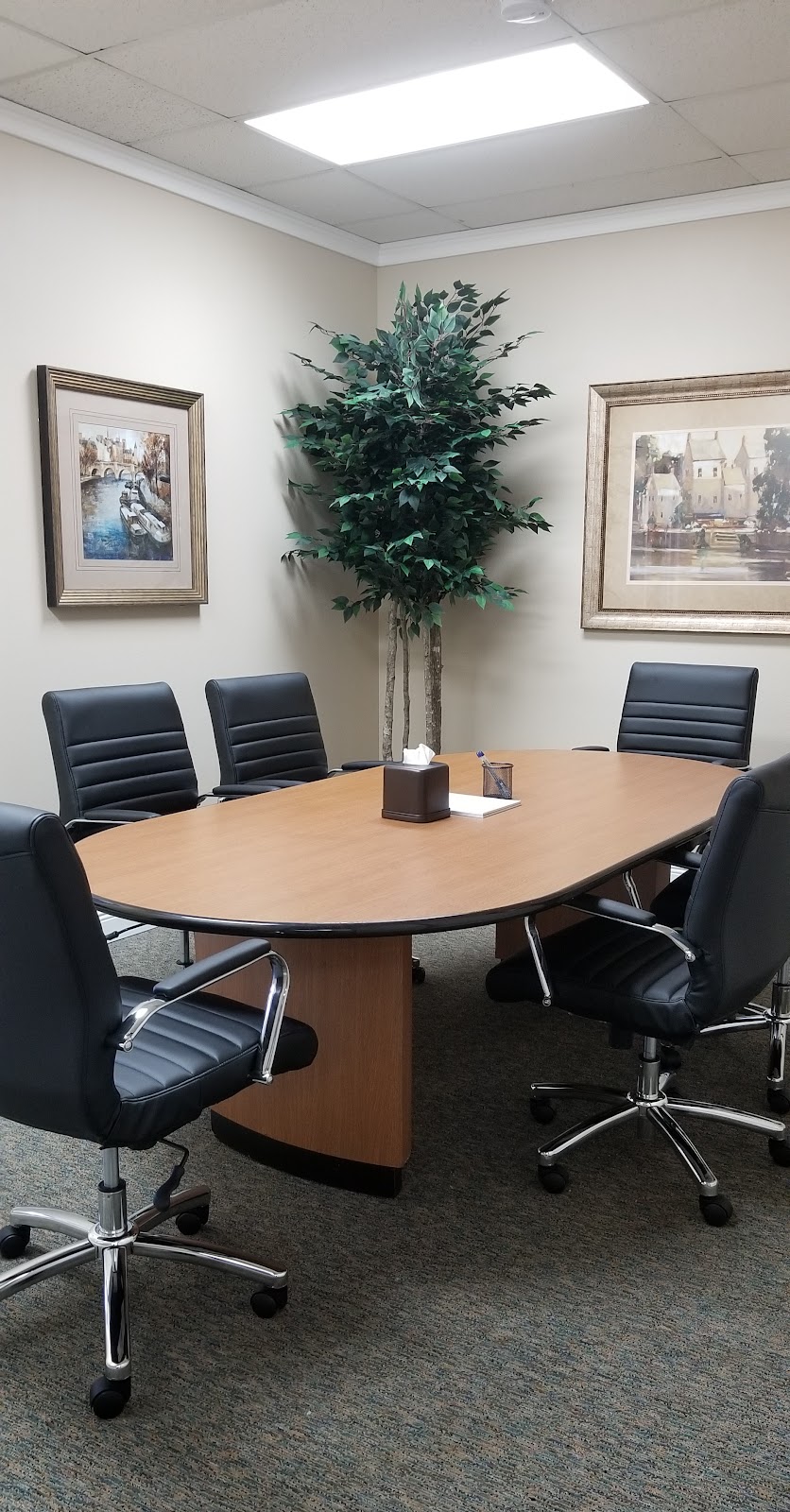 The Rainey & Rainey conference room — an oval wood table with framed art on beige walls