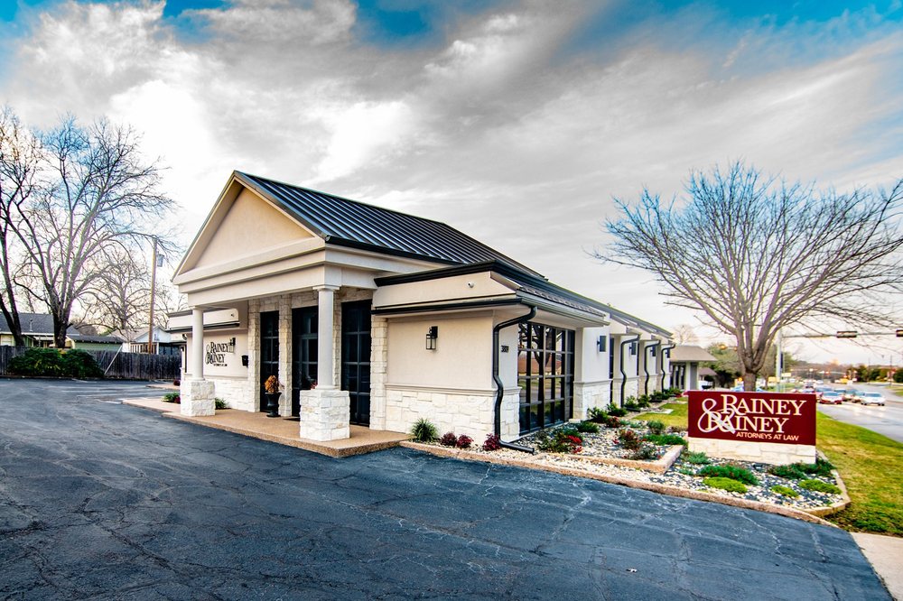 The Rainey & Rainey office building in Waco, with the firm's red monument sign at the street
